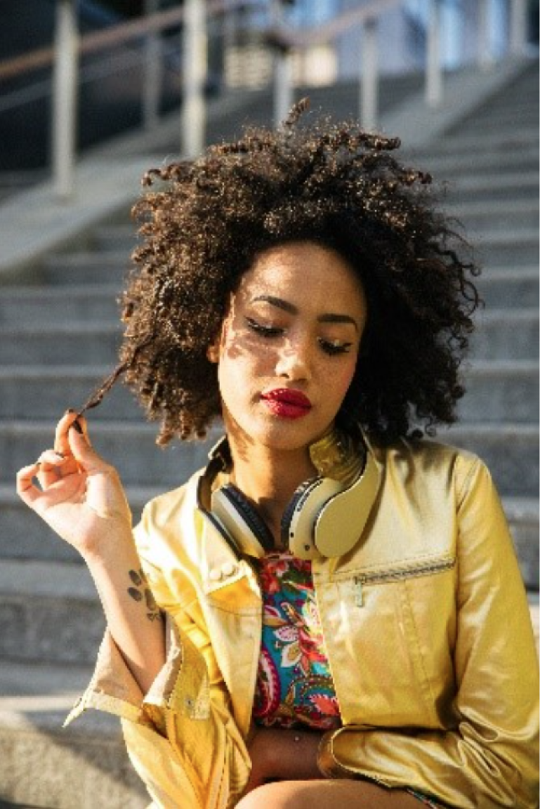 A Model Touching The Curl Of Her Hair While Posing On Camera